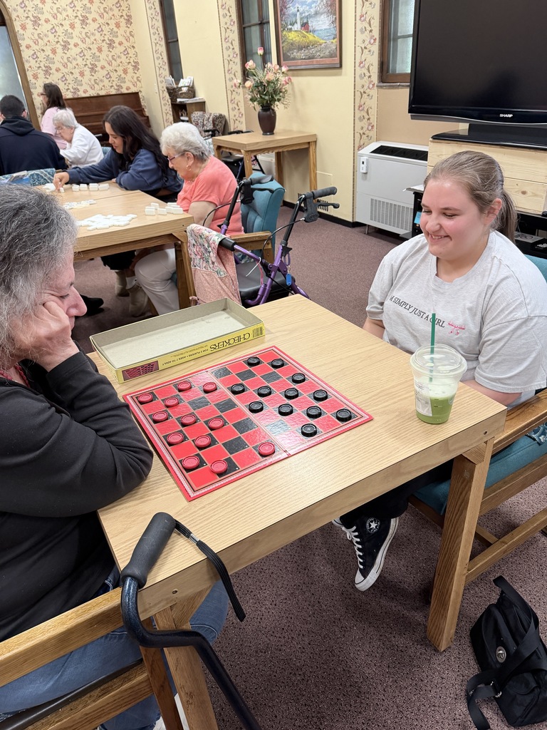A student plays checkers with a senior living resident