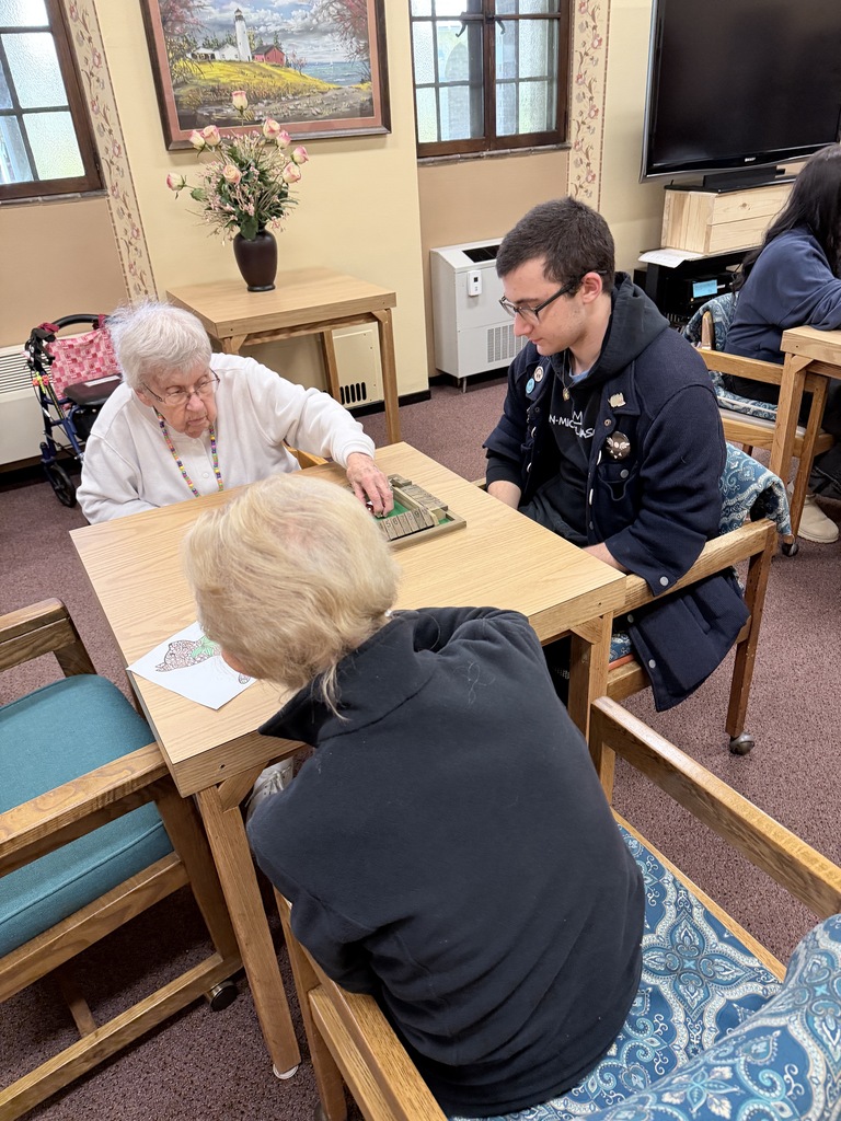 students play dominoes with senior residents