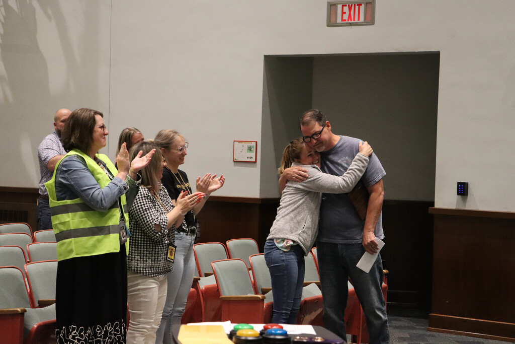 Mr. Rice hugs Mrs. Racinowski as the admin team claps. 