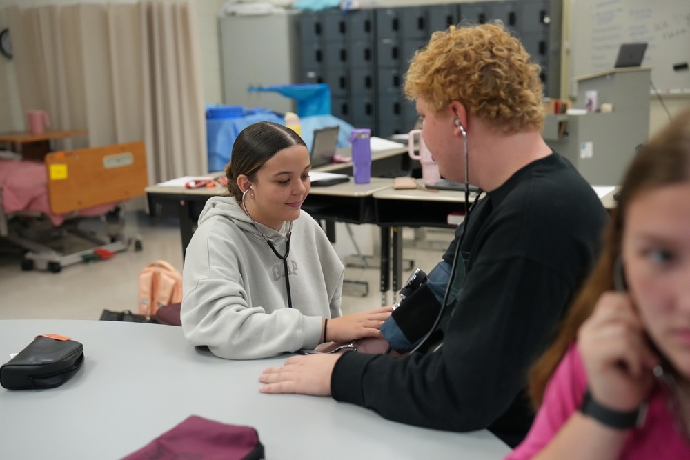 Students in Health Sciences practices using stethoscope.