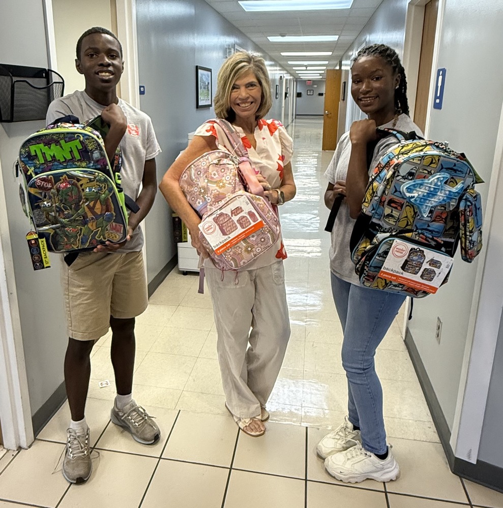 Season of Service representatives present backpacks to SCSD staff.