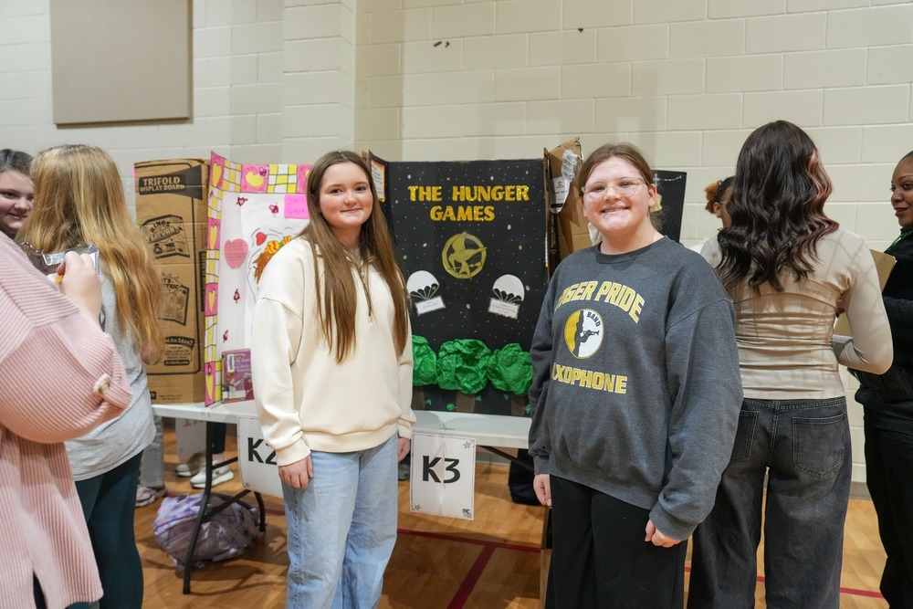 Students standing near their reading fair projects.