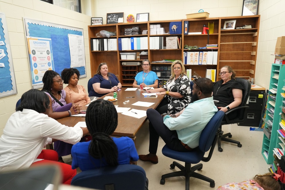 A group of people are sitting a table discussing Career and Technical Education.