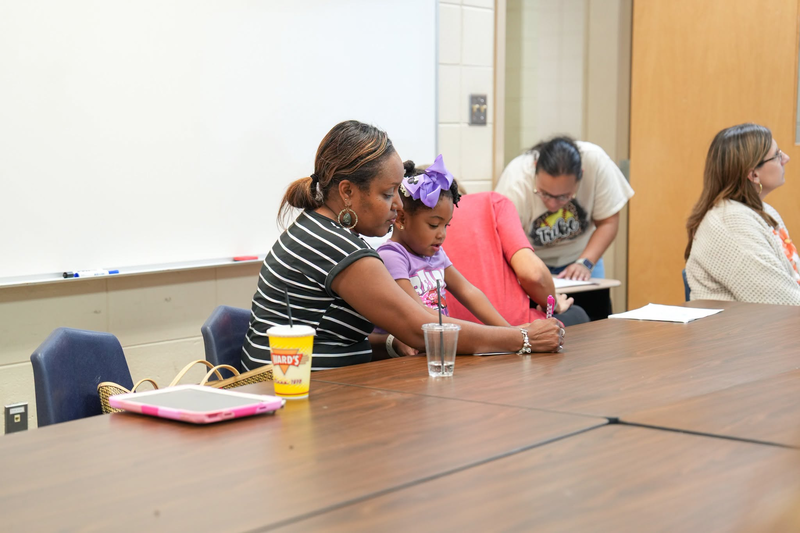 A woman is writing on a piece of paper with her daughter.