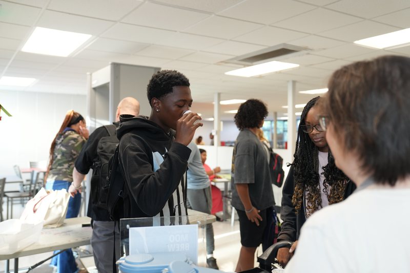 A male high school student is taste testing Moo Brew coffee.