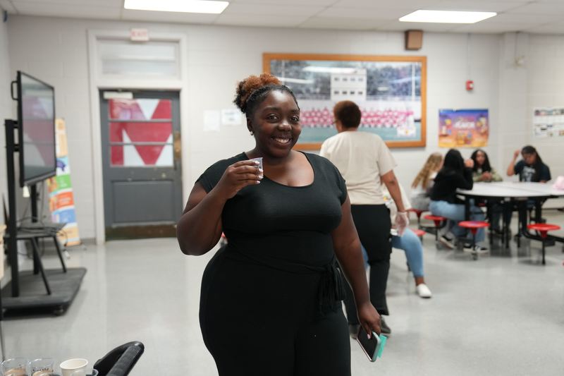 A teacher poses with a cup of Moo Brew