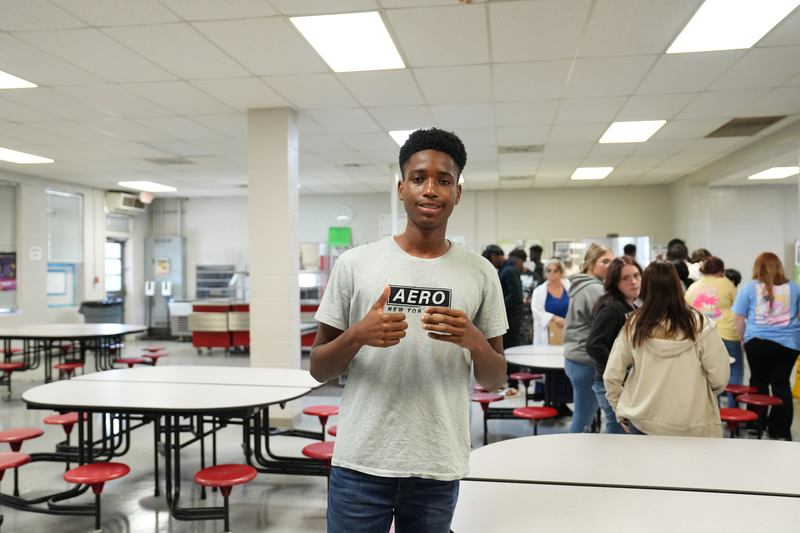 A student poses with a cup of Moo Brew