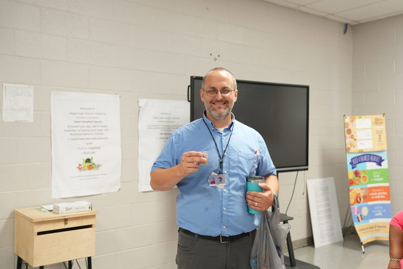 A teacher poses with a cup of Moo Brew