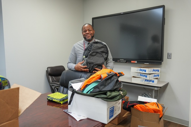 A principal poses with the donated backpacks.