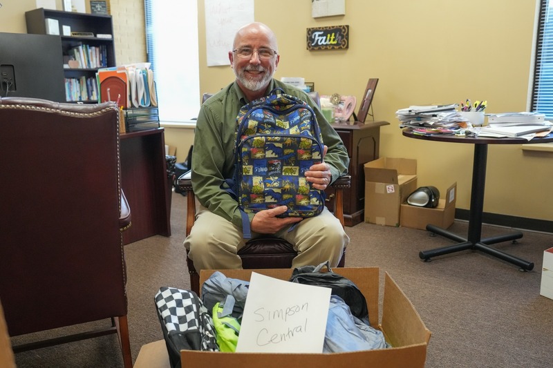 A principal poses with the donated backpacks.