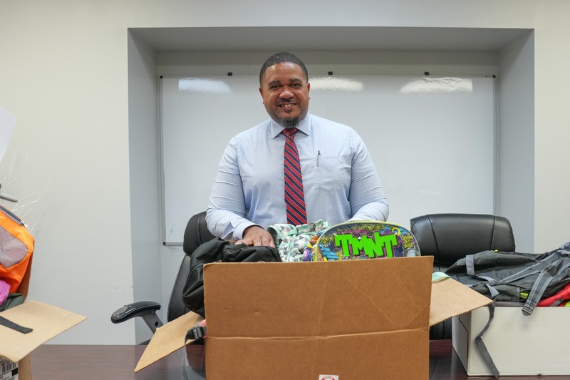 A principal poses with the donated backpacks.