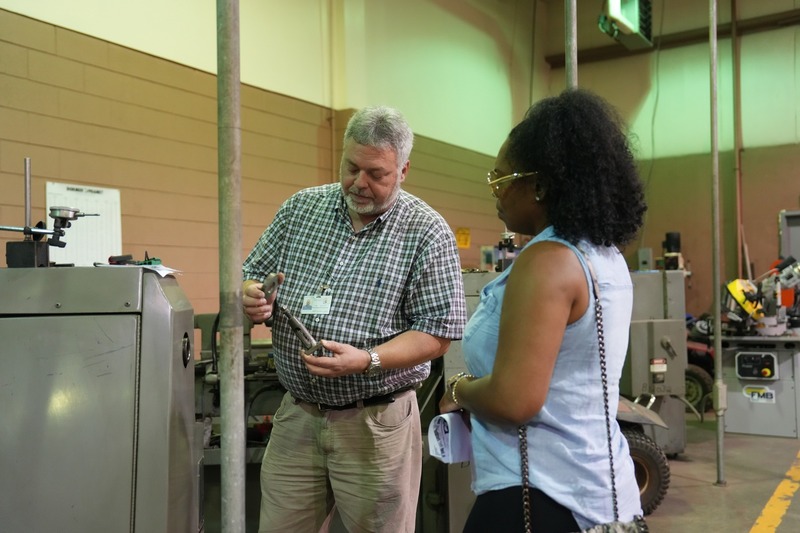 Welding instructor is showing a piece of equipment to a parent.