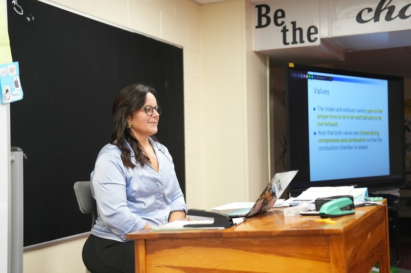 Agriculture and Natural Resources teacher is smiling while talking to a fellow teacher and student.
