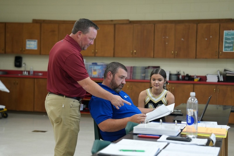 The Law and Public Safety instructor is interacting with a parent and his daughter.