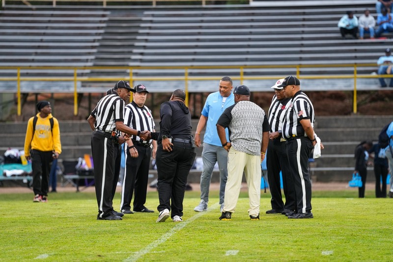 Coaches, administrators, and referees meet before the game