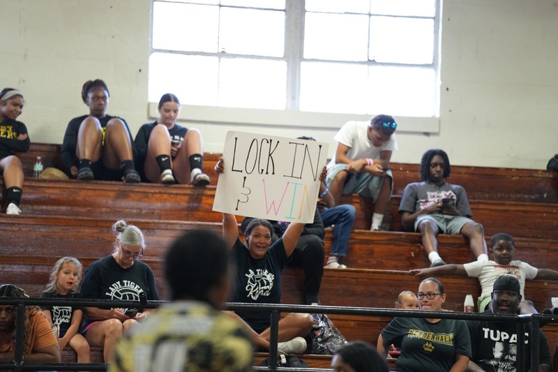 A parent is holding a sign that says "Lock in and win."