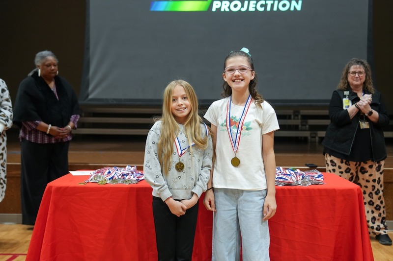 Students standing near their reading fair projects.