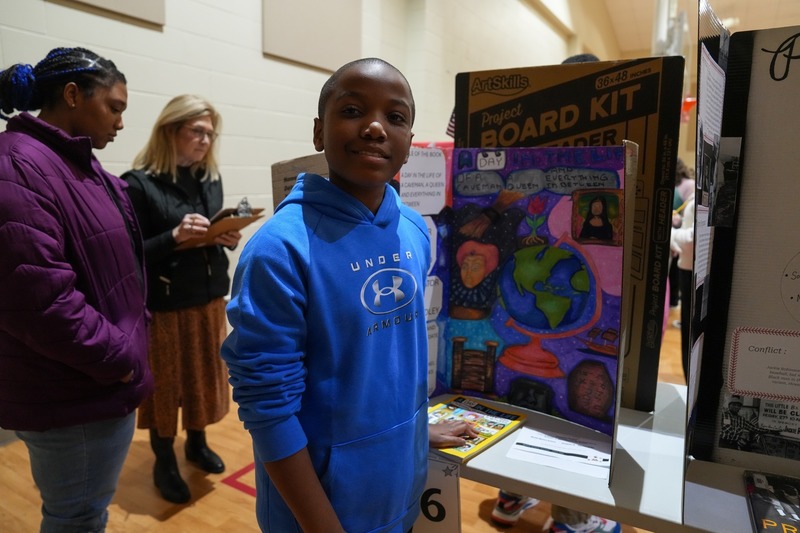 Students standing near their reading fair projects.