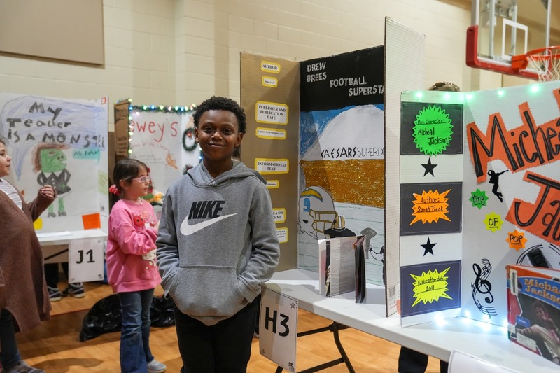 Students standing near their reading fair projects.