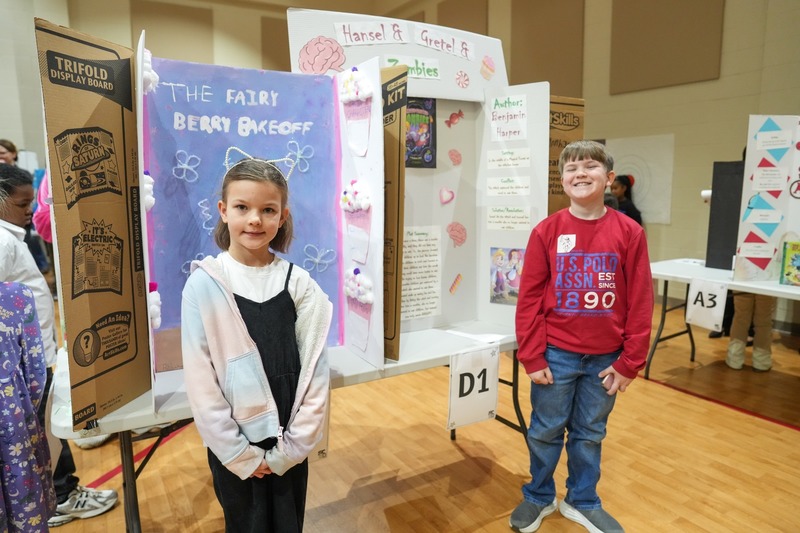 Students standing near their reading fair projects.