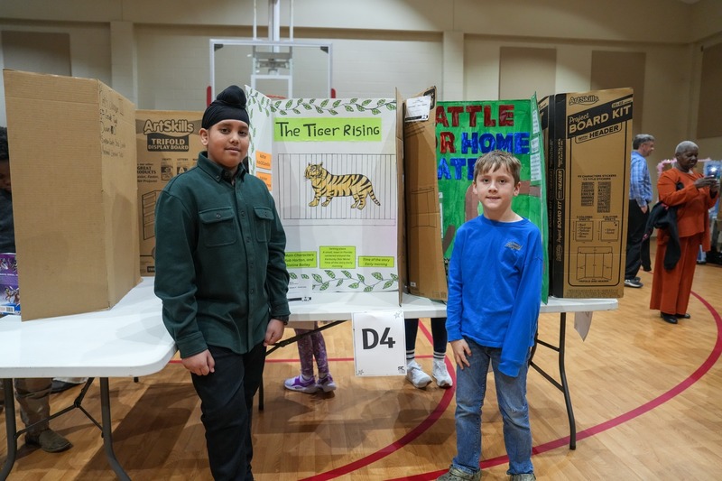 Students standing near their reading fair projects.