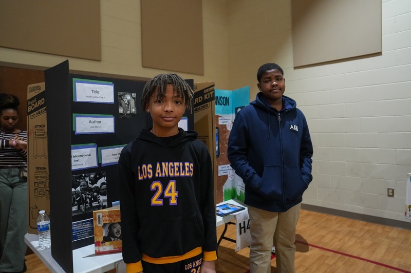Students standing near their reading fair projects.