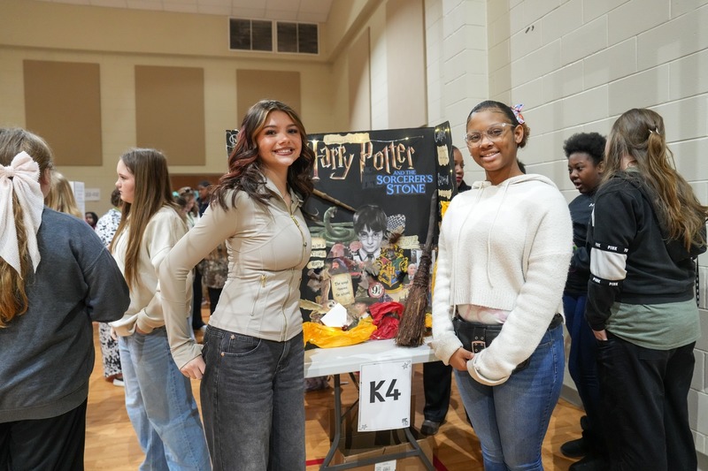Students standing near their reading fair projects.