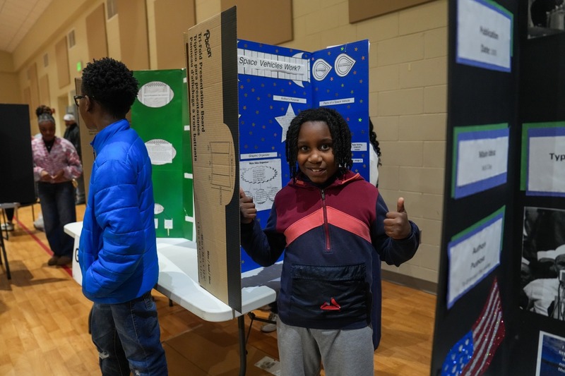 Student standing near their reading fair projects.