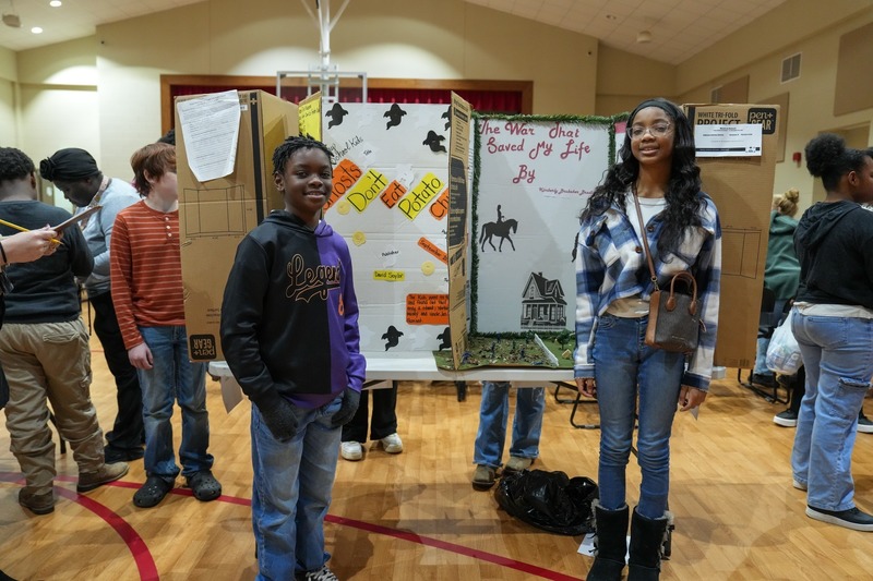 Students standing near their reading fair projects.