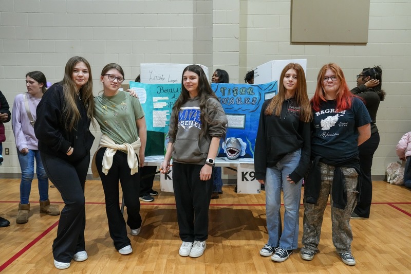 Students standing near their reading fair projects.
