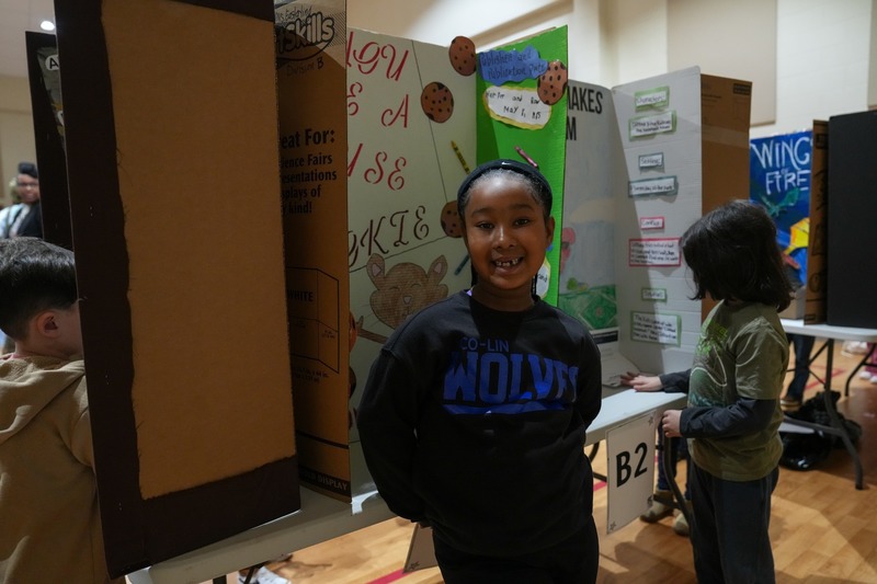 Student standing near their reading fair projects.