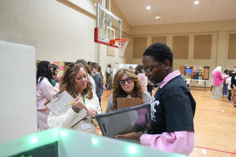 High School student presenting his reading fair project to judges