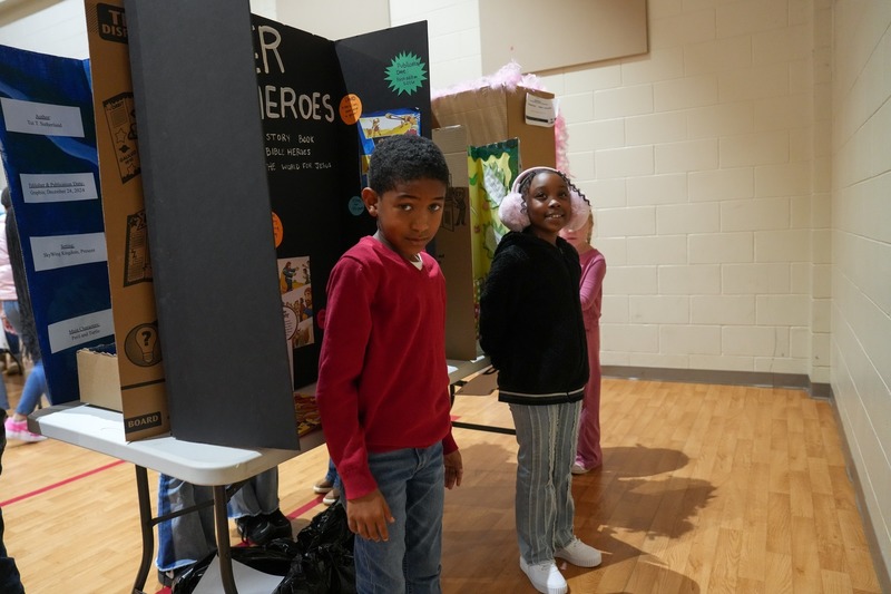 Students standing near their reading fair projects.