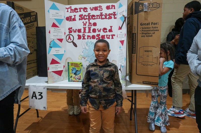 Students standing near their reading fair projects.
