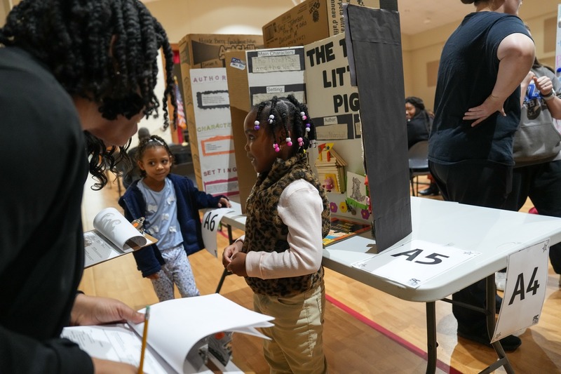 Students standing near their reading fair projects.