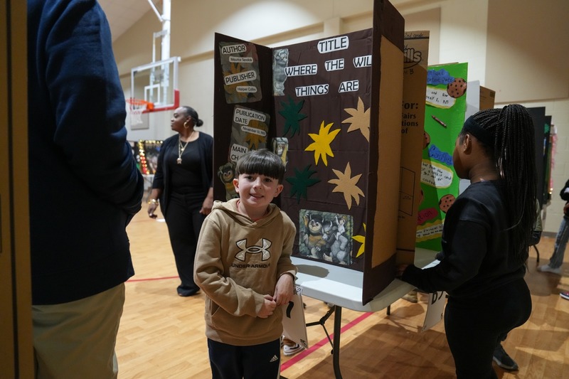 Students standing near their reading fair projects.