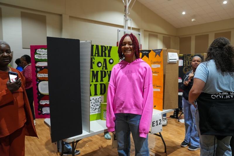 Students standing near their reading fair projects.