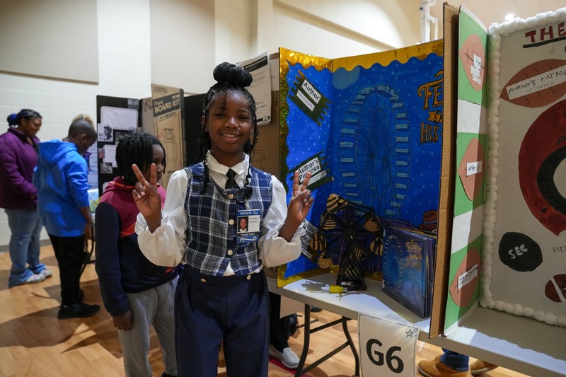 Students standing near their reading fair projects.