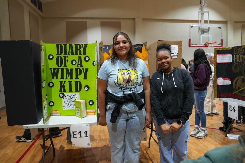 Students standing near their reading fair projects.
