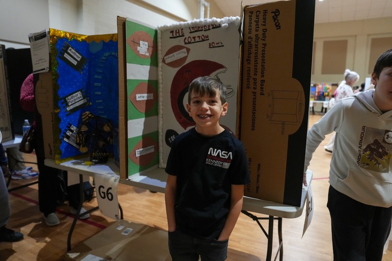 Students standing near their reading fair projects.