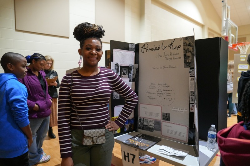 Students standing near their reading fair projects.