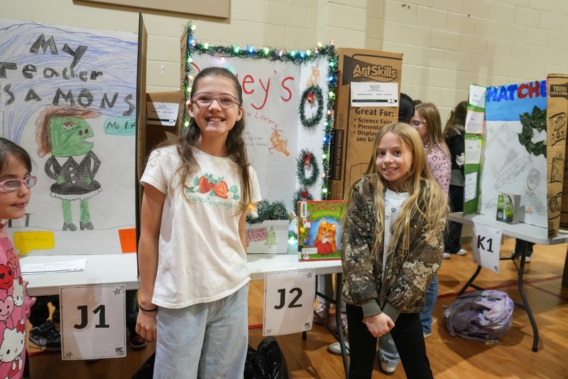 Students standing near their reading fair projects.