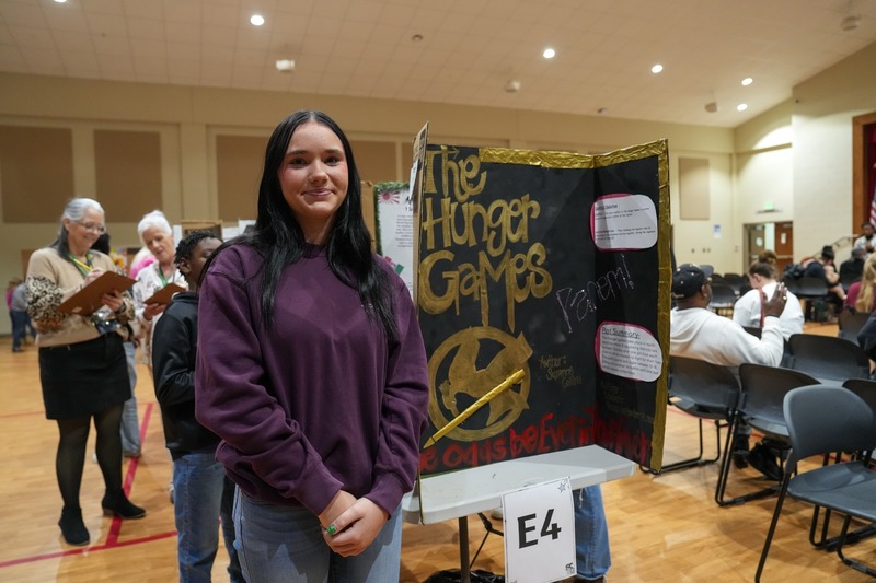 Students standing near their reading fair projects.