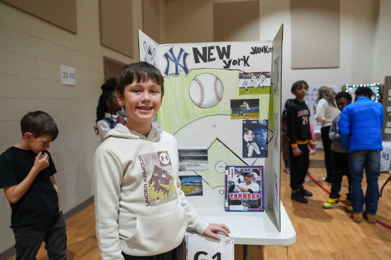 Students standing near their reading fair projects.