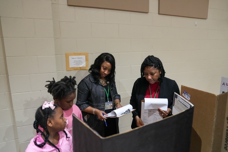 Students standing near their reading fair projects.
