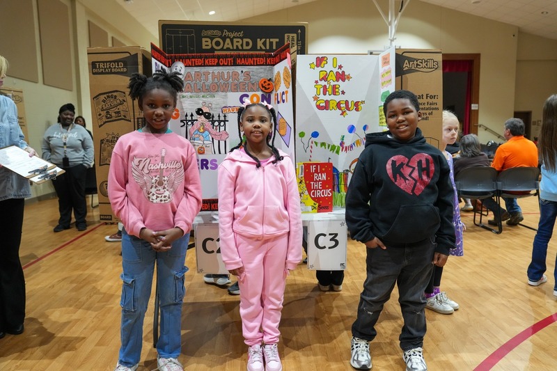 Students standing near their reading fair projects.