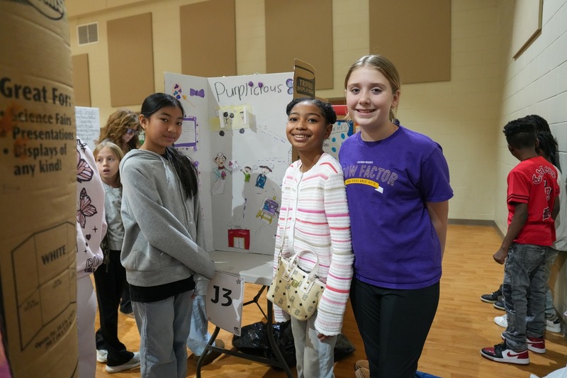 Students standing near their reading fair projects.