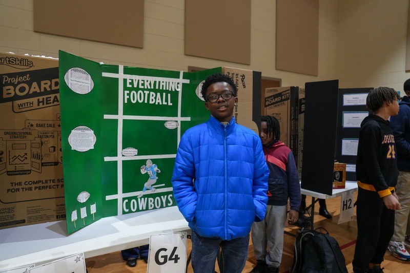 Students standing near their reading fair projects.