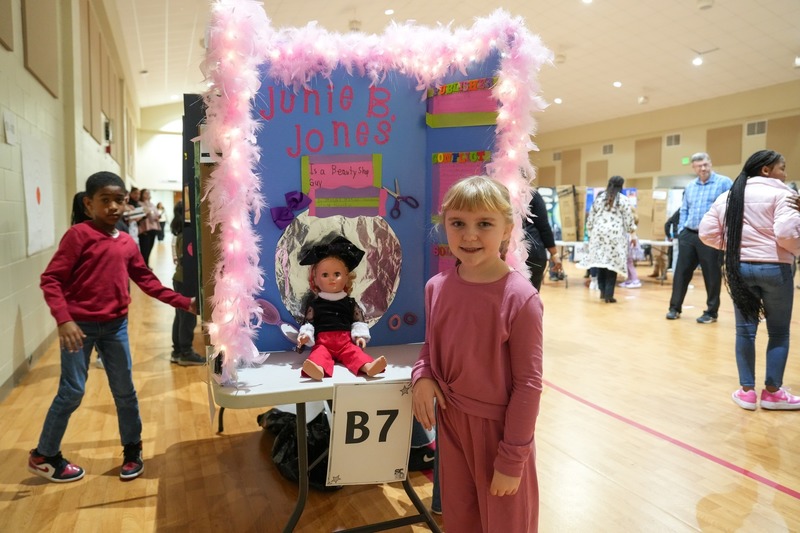 Students standing near their reading fair projects.