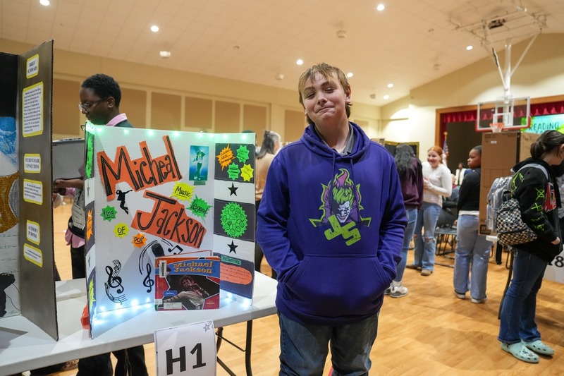 Students standing near their reading fair projects.